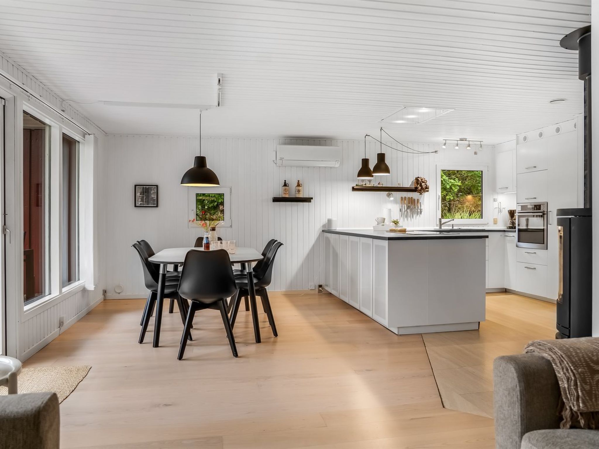 A modern kitchen with white cabinetry, a central island, and a dining area with a table and chairs.