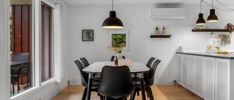 A dining area with a round table, black chairs, pendant lighting, and a view of the outdoors.