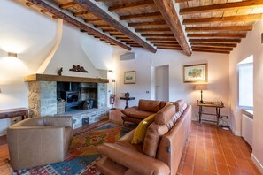 A cozy living room with a stone fireplace, leather sofas, and exposed wooden beams.
