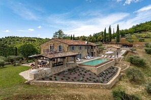 Eine Steinvilla mit Swimmingpool, Sitzgelegenheit im Freien und einem Garten.