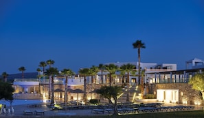A resort with outdoor seating, palm trees, and a pool area.