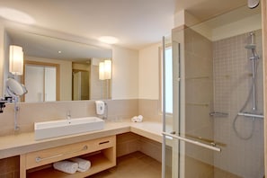 A modern bathroom with a large mirror, a sink, a glass-enclosed shower, and a towel rack.