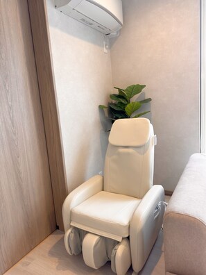 A massage chair with a footrest, a potted plant, and a wall-mounted air conditioner. - sugi villa (Kitanominecho, Furano)
