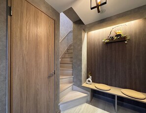 Ein modernes Interieur mit einer Holztür, einer Treppe und einer Bank mit Kissen.