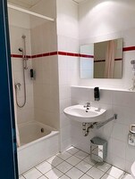 Un baño con ducha, lavabo y espejo.