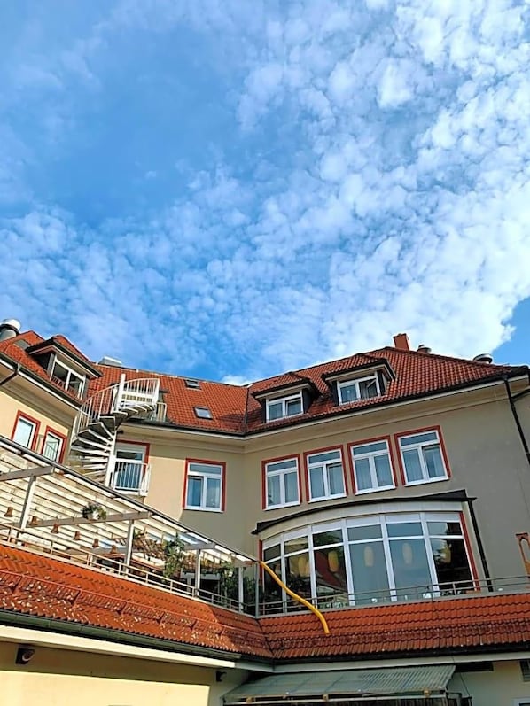 Ein mehrstöckiges Gebäude mit rotem Ziegeldach, einem Balkon und einer Treppe.