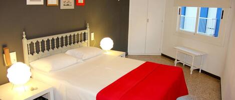 A bedroom with a bed, bedside tables, a wardrobe, and a window.