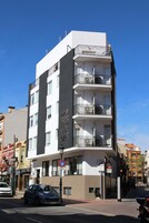 A multi-story hotel with balconies, a sign indicating it is a hotel, and a no parking sign.