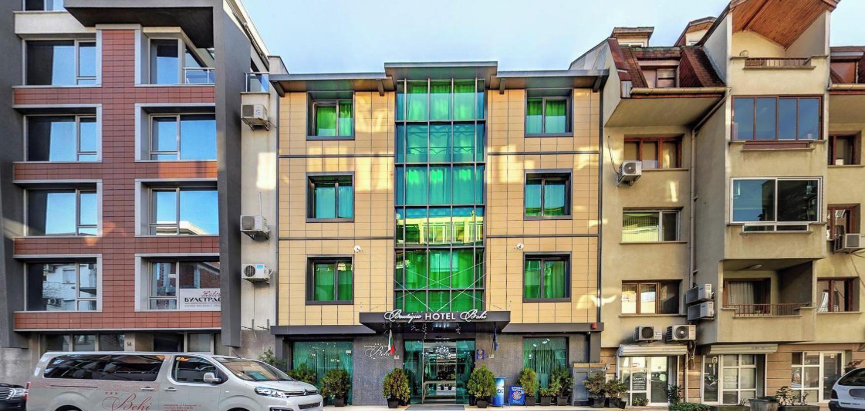 A hotel with a modern facade, multiple balconies, and a central entrance with a sign.