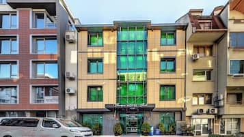 A hotel with a modern facade, multiple balconies, and a central entrance with a sign.