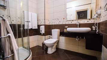 Een badkamer met een glazen douchecabine, toilet, wastafel met spiegel erboven en een handdoekrek.