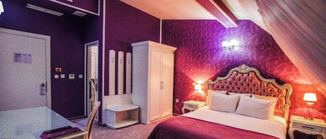 A bedroom with a bed, a wardrobe, a desk, and a mirror.