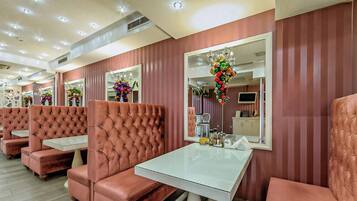 A salon with tufted leather chairs and tables, mirrors, and decorative floral arrangements.