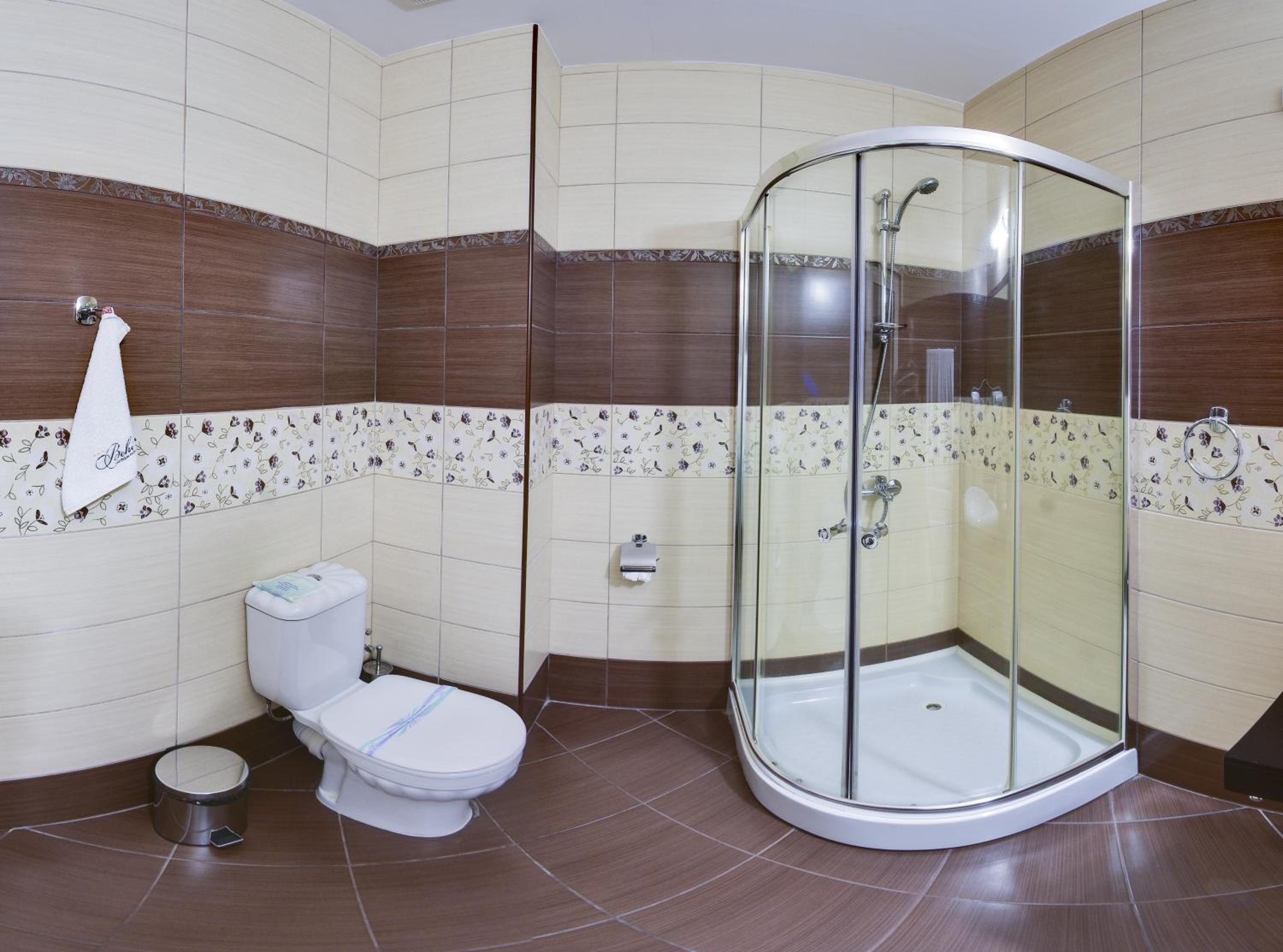 Casa de banho com sanita, bidé e cabine de duche com parede de vidro.