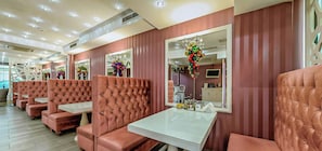 Un salón con sillones de cuero capitonados, mesas, espejos y arreglos florales decorativos.