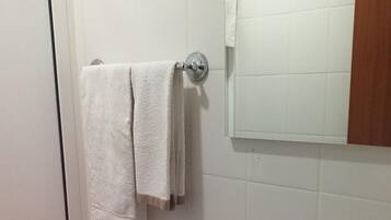 A bathroom with a toilet, a sink, a mirror, and a towel rack.