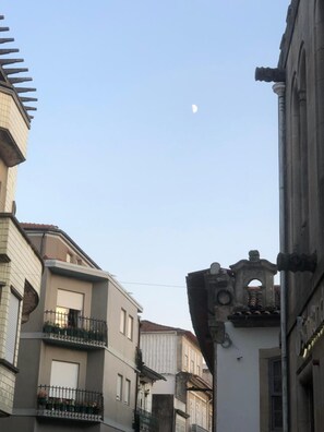 A narrow street with buildings on either side, a clear sky, and a crescent moon. - Residencial Encontro (Vila Real)