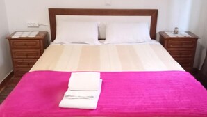 A bed with a wooden frame, white bedding, and a pink blanket. - Residencial Encontro (Vila Real)
