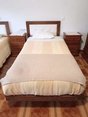 A standard hotel room with a single bed, two wooden nightstands, and a wooden headboard. - Residencial Encontro (Vila Real)