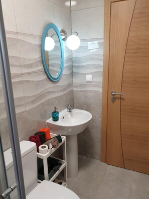 A bathroom with a white sink, a mirror, and a wooden door. - Lisbon Hostel Terminal 4 (Lisbon)