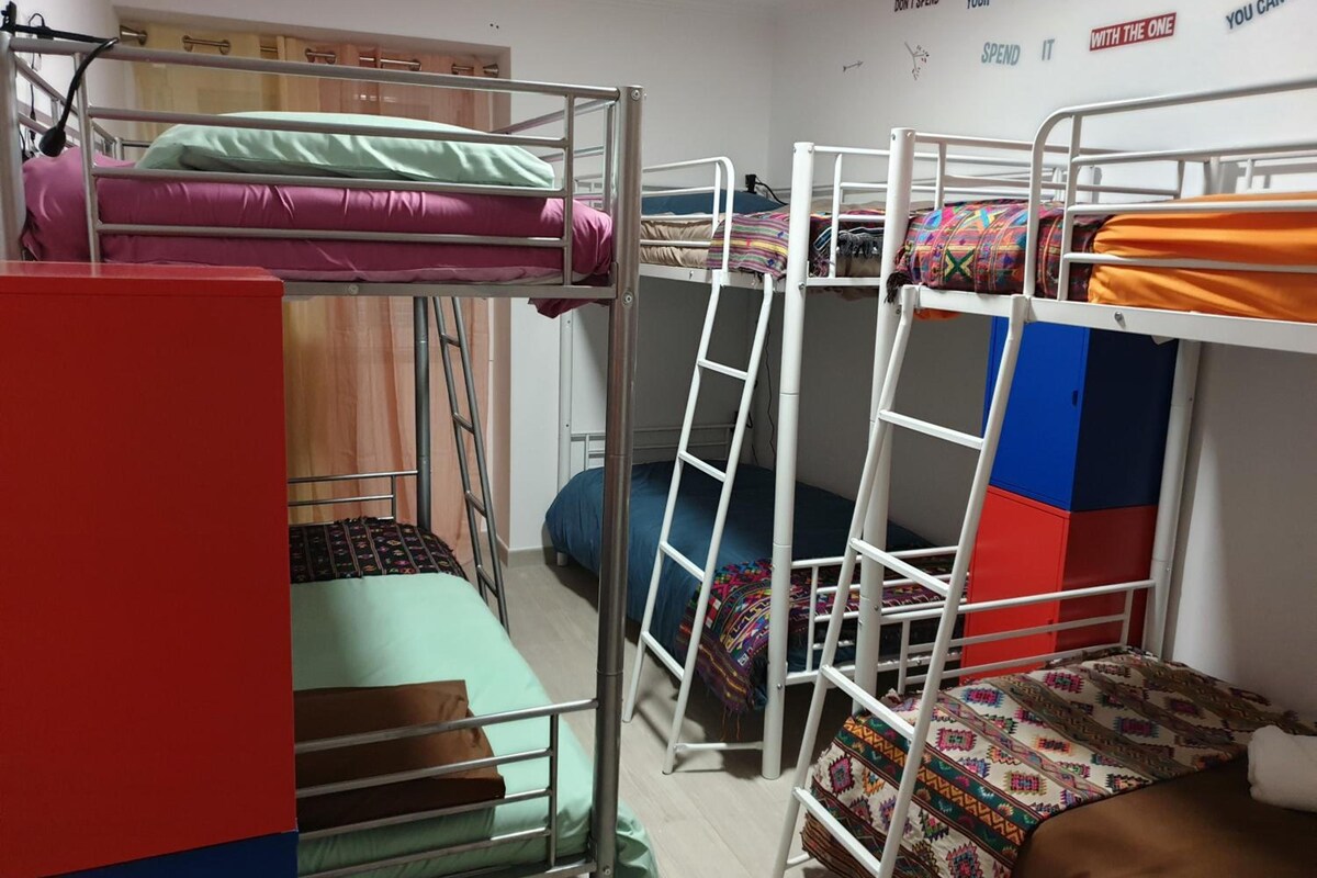 Une chambre de dortoir avec des lits superposés, un bureau rouge et un mur orné de citations inspirantes.