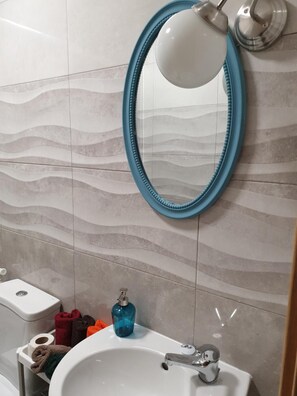 A bathroom with a white sink, a blue-framed mirror, and a wall-mounted light fixture. - Lisbon Hostel Terminal 4 (Lisbon)