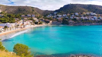 Un pueblo costero con edificios a lo largo de la playa y un mar azul y transparente.