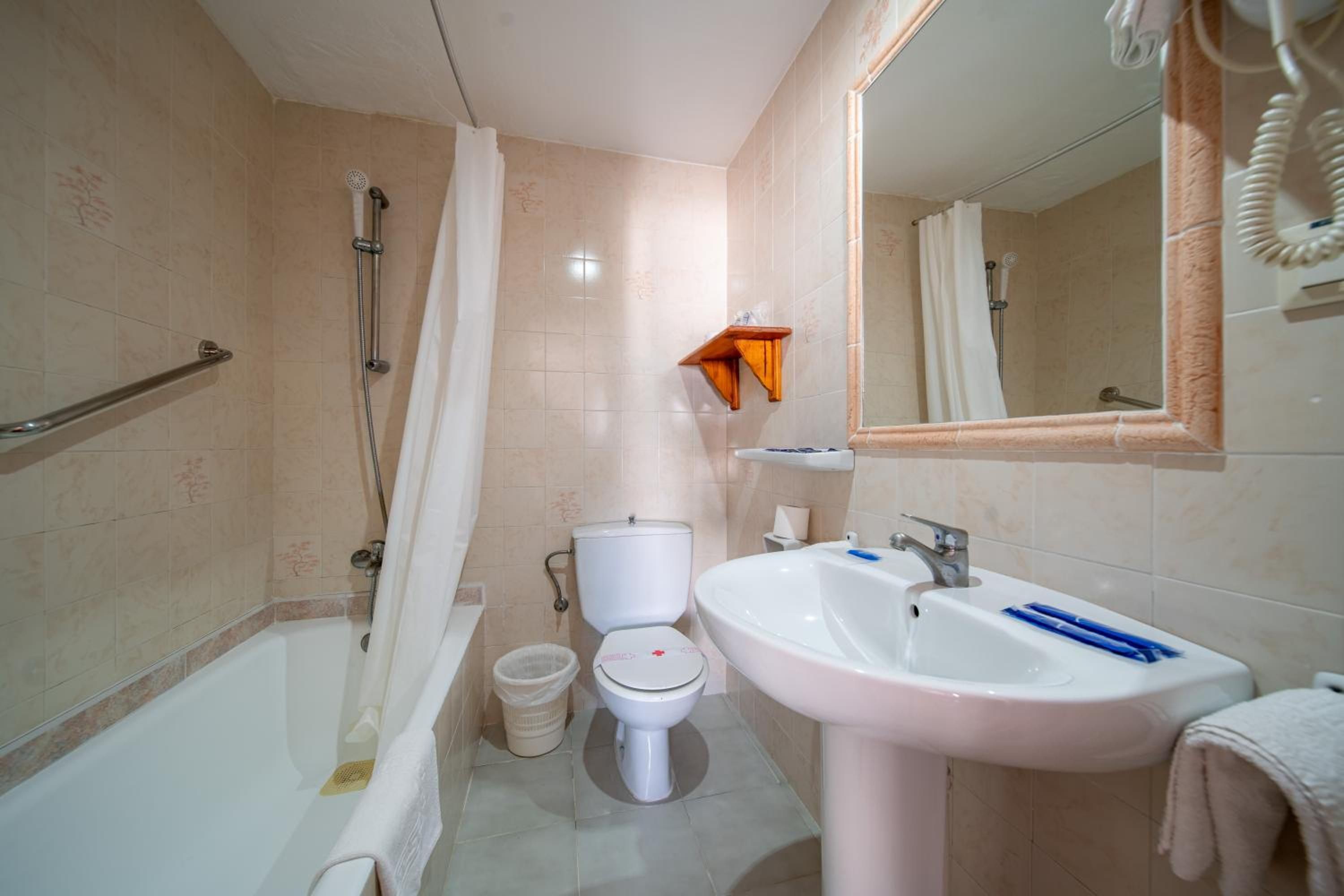 Un baño con bañera, inodoro, lavabo y espejo.