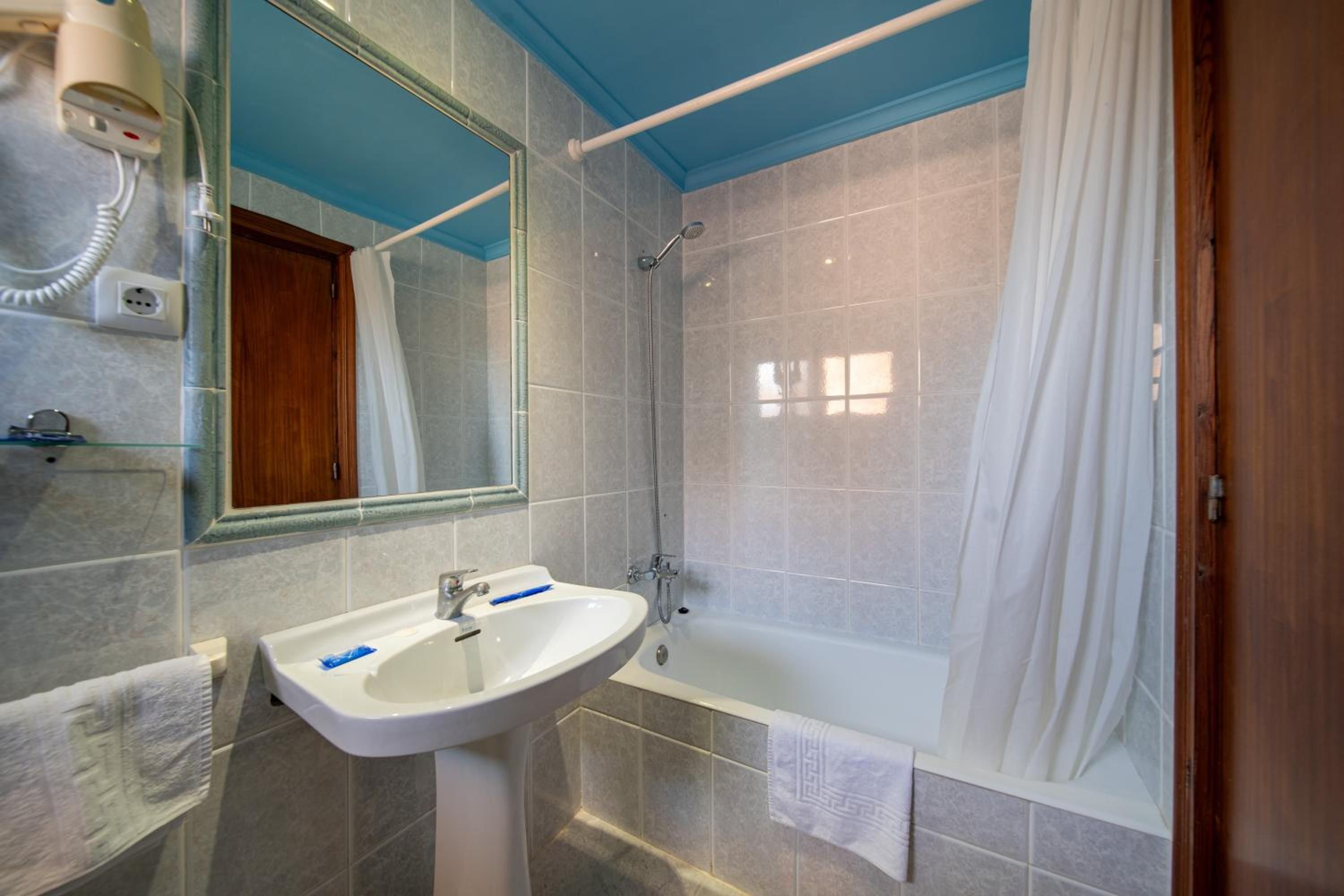 Un baño con lavamanos blanco, espejo, ducha y bañera.