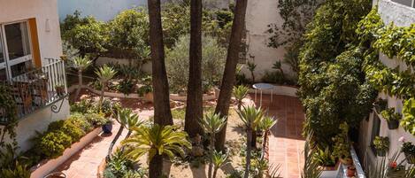 Un patio con una mesa redonda y sillas, rodeado de plantas y árboles.