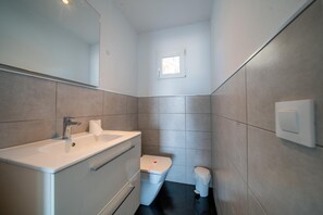 A modern bathroom with a white sink, mirror, and toilet. - Hotel Buigues (Teulada)