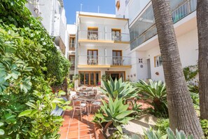 A courtyard with a dining area, surrounded by white buildings with balconies. - Hotel Buigues (Teulada)