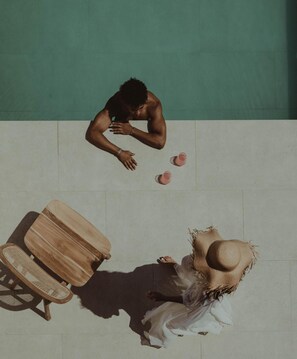 A swimming pool with a person lying on the edge and another person sitting on a chair. - Seven Rocks Chalkidiki (Kassandra)