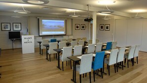 Un salón de conferencias con una pantalla de presentación, un atril y filas de sillas.