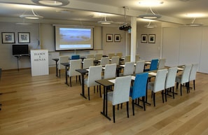 A conference room with a presentation screen, a podium, and rows of chairs. - Hamn I Senja (Senja)