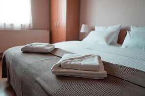 A hotel room with a neatly made bed, a folded towel on the bed, and a window with curtains. - Hotel Topcider (Belgrade)