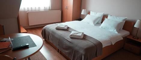 A hotel room with a bed, bedside tables, a desk, and a radiator.