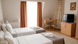 A hotel room with two beds, a desk, a chair, a television, and a radiator. - Hotel Topcider (Belgrade)