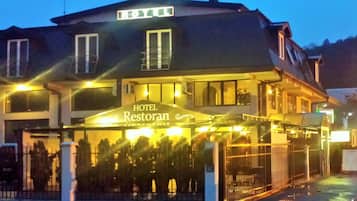A hotel with a sign reading 'HOTEL Restoran' and a covered outdoor seating area.