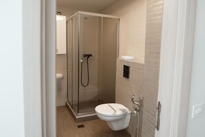 Un baño moderno con ducha envuelta en vidrio, inodoro y lavamanos.