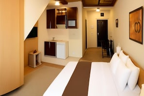 A hotel room with a bed, a small kitchenette, a mirror, a door, and a wall-mounted artwork. - Hotel Topcider (Belgrade)