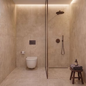 Un baño moderno con ducha, inodoro y un taburete pequeño con una toalla.