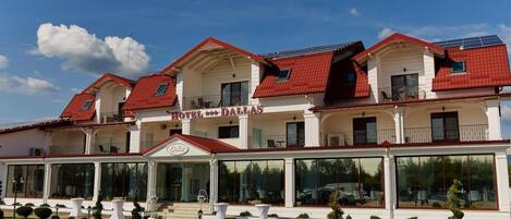 Un hotel con techo rojo, varios balcones y un área de entrada cubierta.