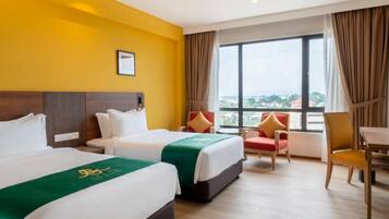 A hotel room with two beds, a view of the city, and a dining area.