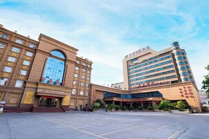 Un hotel con una amplia entrada central, varios pisos y un diseño moderno.