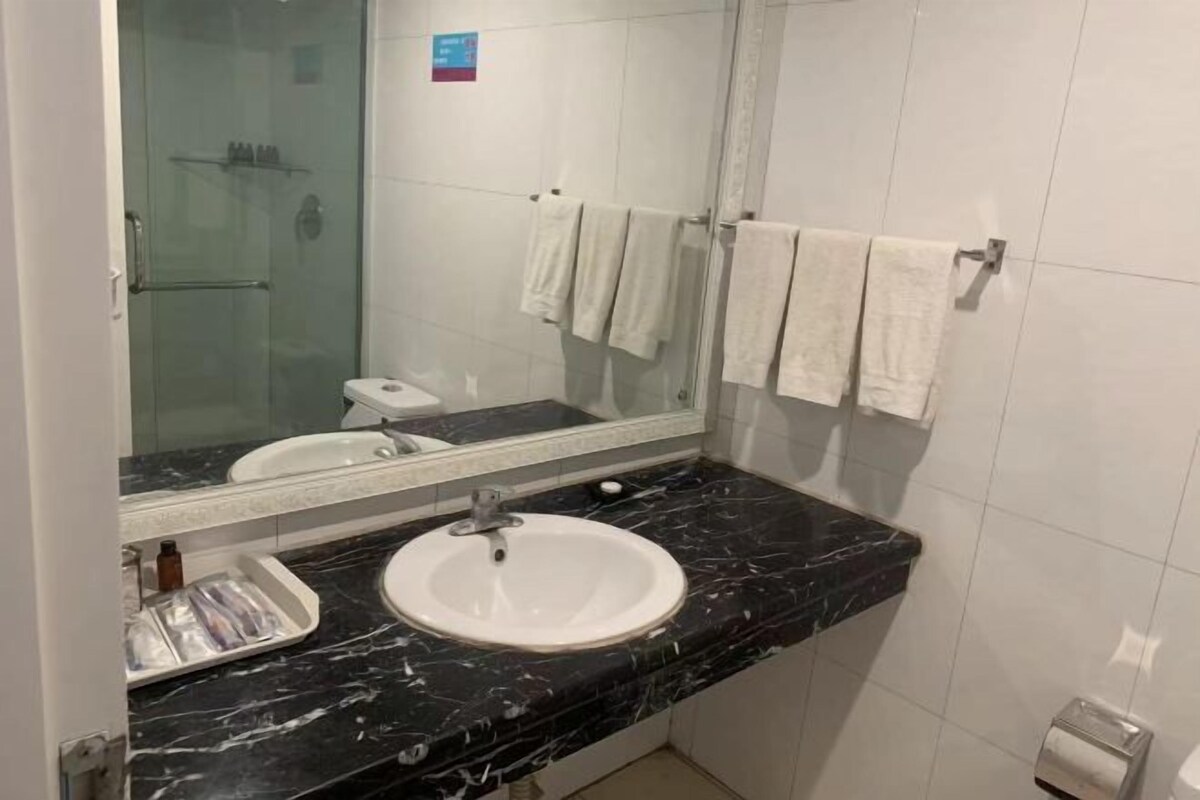A bathroom with a white sink, a glass shower enclosure, and a mirror.