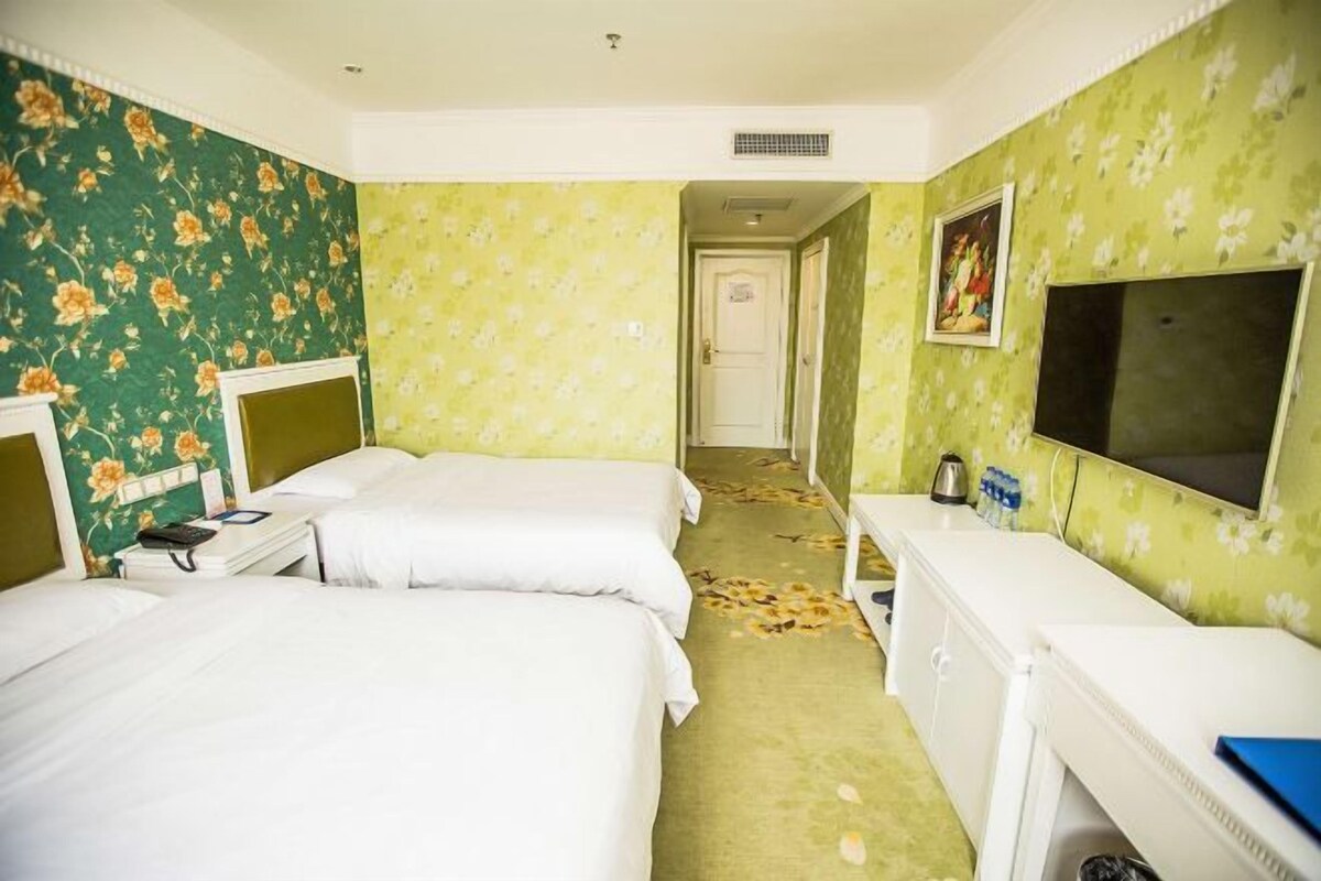 A hotel room with two beds, a television, and a bathroom.