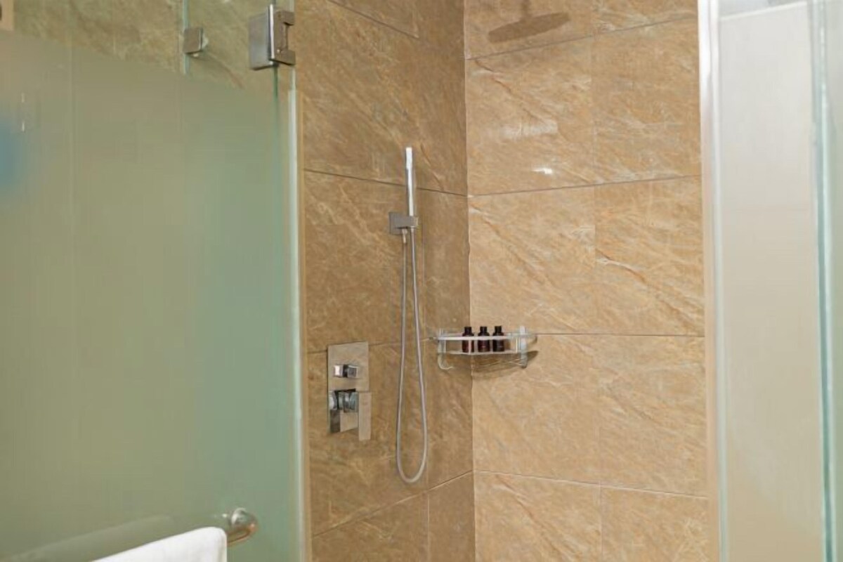 A shower with a handheld showerhead and a wall-mounted control panel.