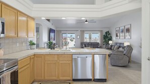 A modern kitchen with wooden cabinets, a dishwasher, and a central island. - Desert Horizon Retreat - Pool, Spa & Desert Views (Lake Havasu City)