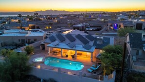 A residential property with a swimming pool, solar panels, and a view of the surrounding neighborhood. - Desert Horizon Retreat - Pool, Spa & Desert Views (Lake Havasu City)